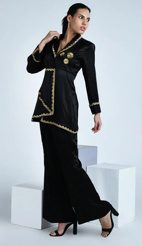 Female model in a side-profile pose glancing over her shoulder, wearing a black embellished outfit